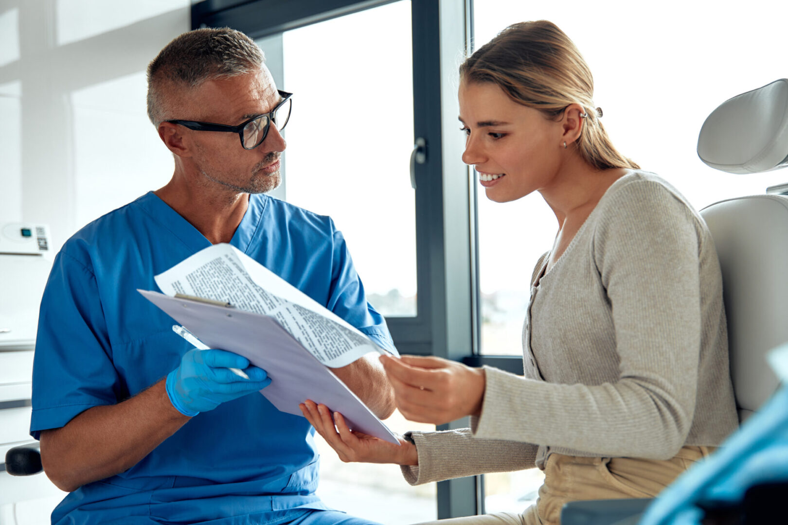 A dedicated healthcare professional is engaging in a detailed discussion about medical documents with a patient in a bright and contemporary setting that is designed for comfort and support
